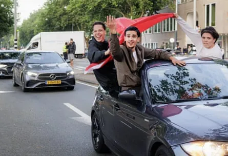 Morocco fans with a flag lean out of car on the streets on Amsterdam to celebrate the World Cup win over the Netherlands.