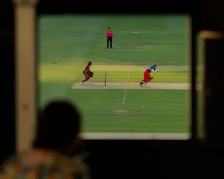 England’s captain Charlie Dean plays a shot as a scorer watches through a window in the scoreboard.