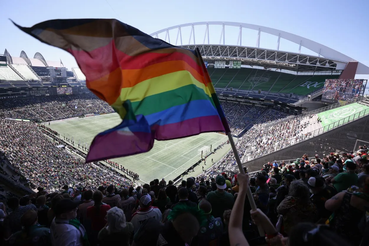 A fan waves a Pride flag at a Seattle Sounders match at Lumen Field in June 2023