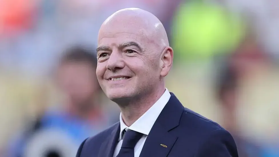 Head and shoulders of a smiling Gianni Infantino, wearing a dark suit and tie