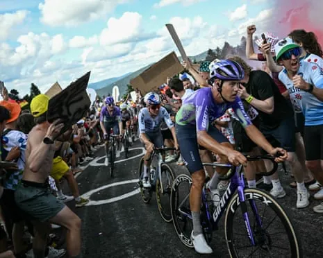 Tom Pidcock on the wheel of Luke Plapp as Mauro Schmid gives chase, surrounded by fans