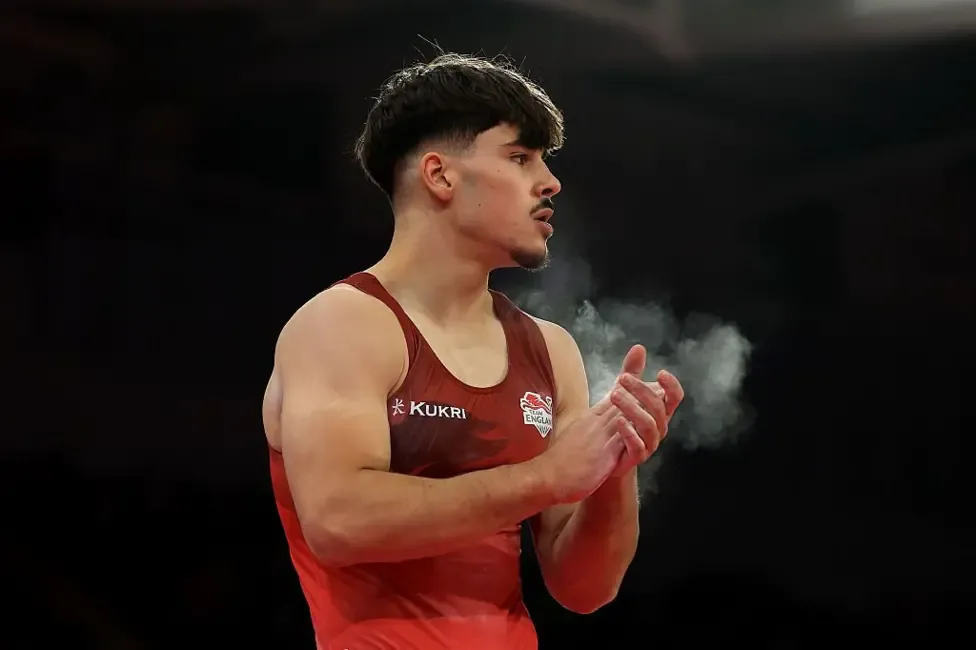 Gabriel Langton claps his hands covered with chalk while wearing a red England vest