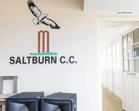 A wall with a logo showing a bird and cricket stumps above the text 'SALTBURN C.C.'