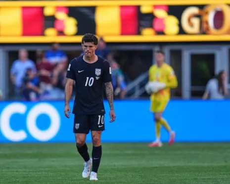 Christian Pulisic in a black number 10 jersey walks on a field looking downward